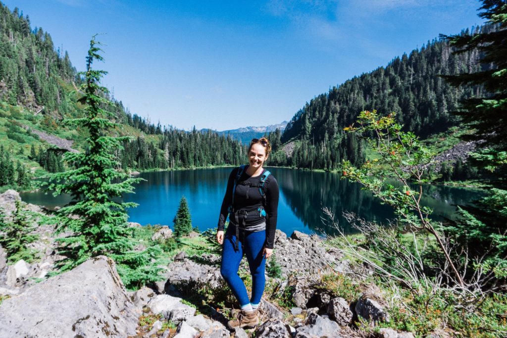 hiker posing in front of a blue alpine lake