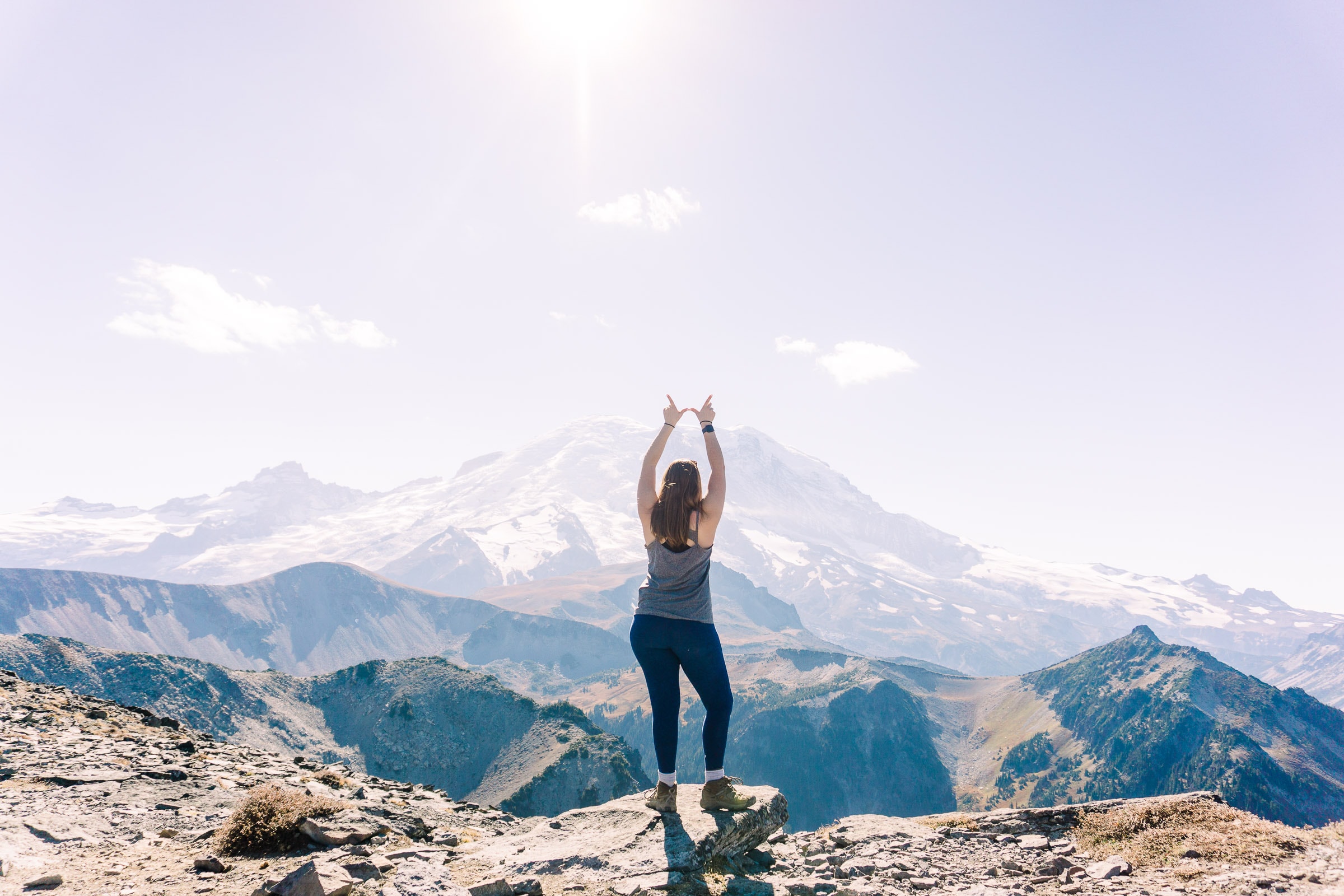Photographer Alexandria Odekirk with arms raised on top of Mount Rainer