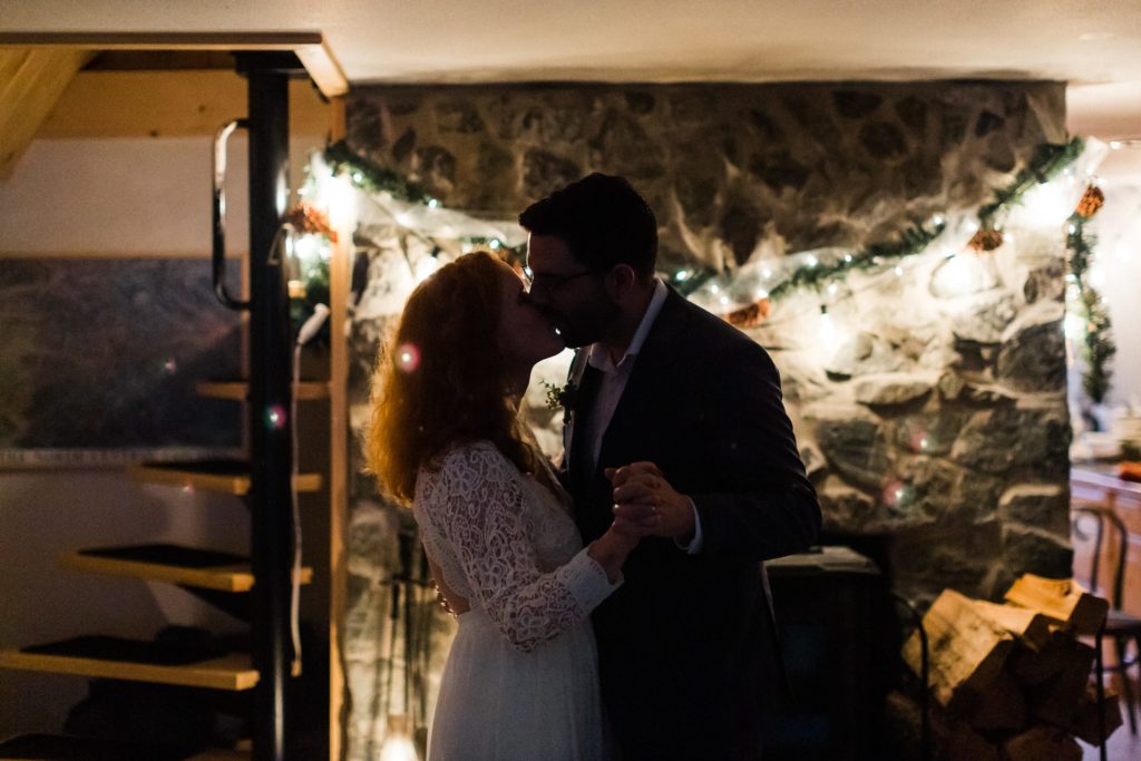 couple enjoys first dance by fireplace with twinkle lights