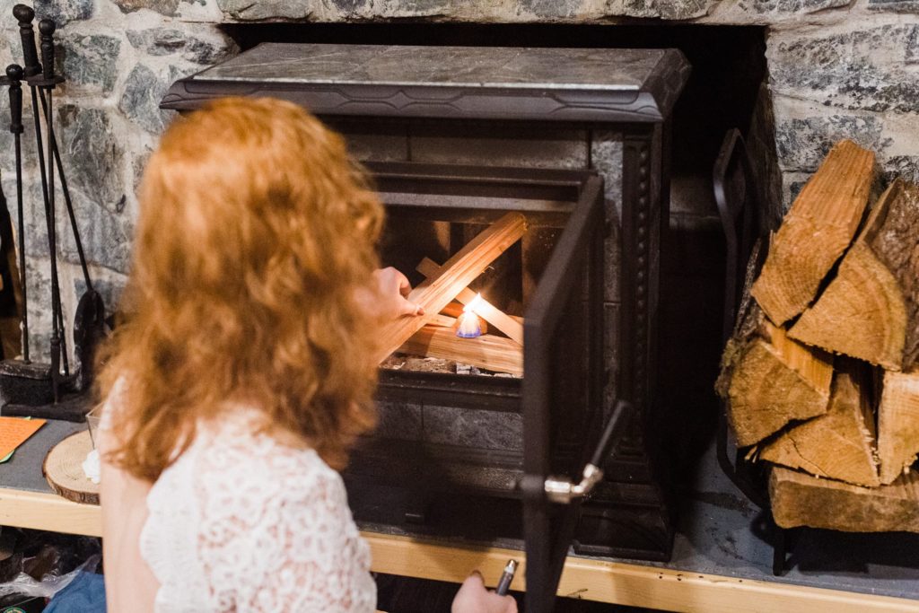 woman lighting an indoor fireplace