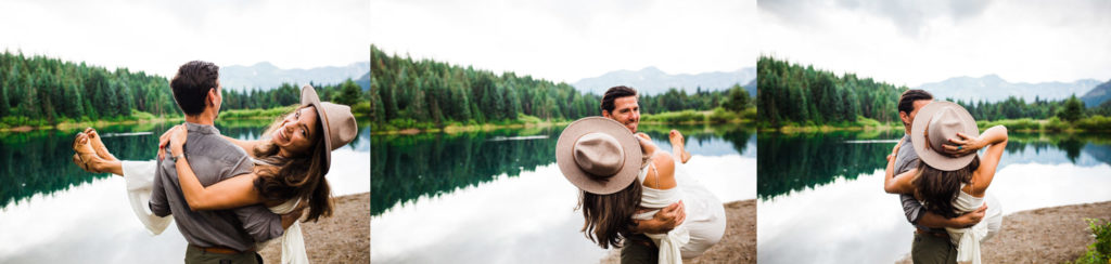 Man spinning woman around in boho hat and white dress in the mountains by a lake. 
