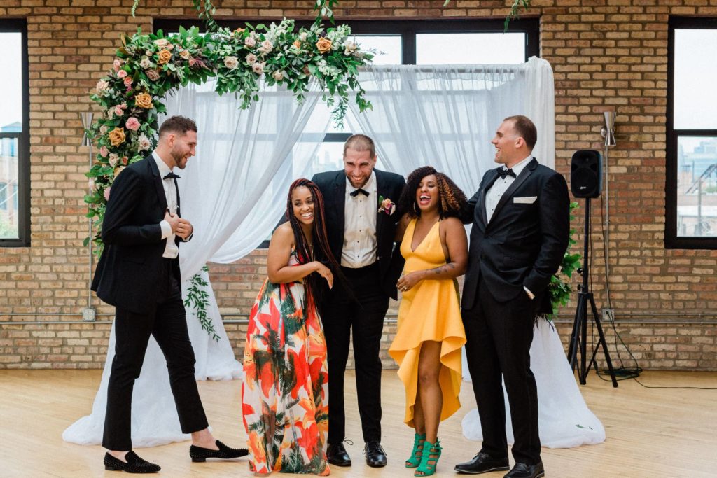 laughing friends in front of wedding arch