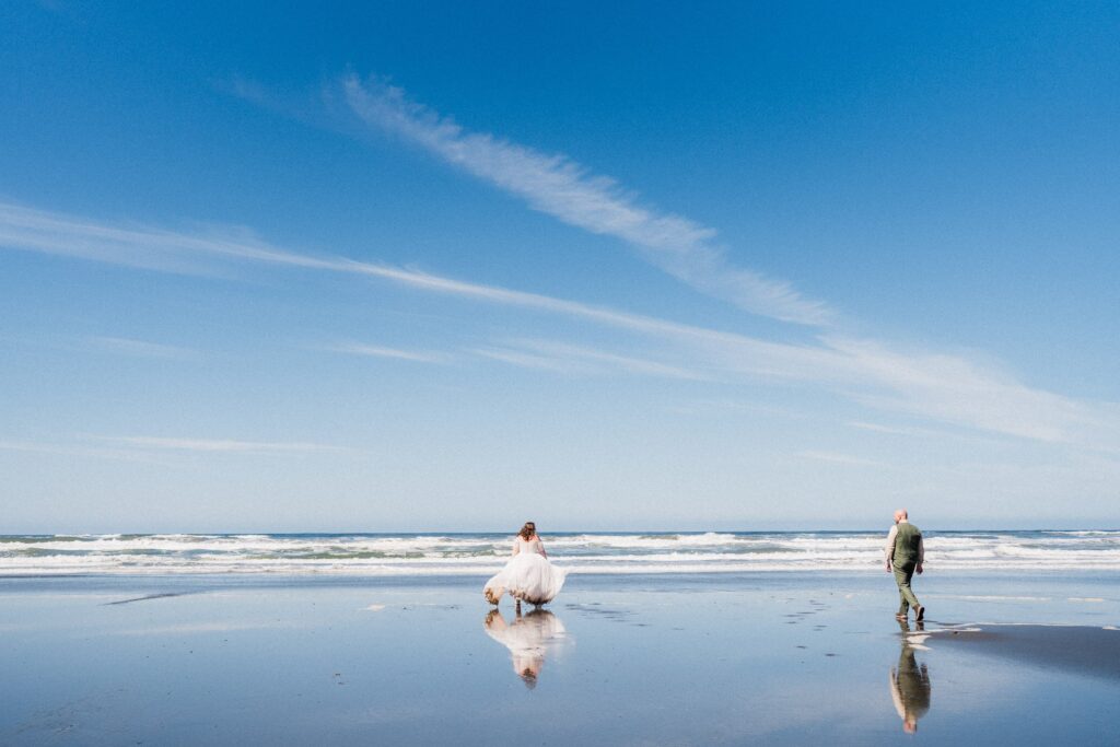 couple running on Kalaloch beach in wedding attire 