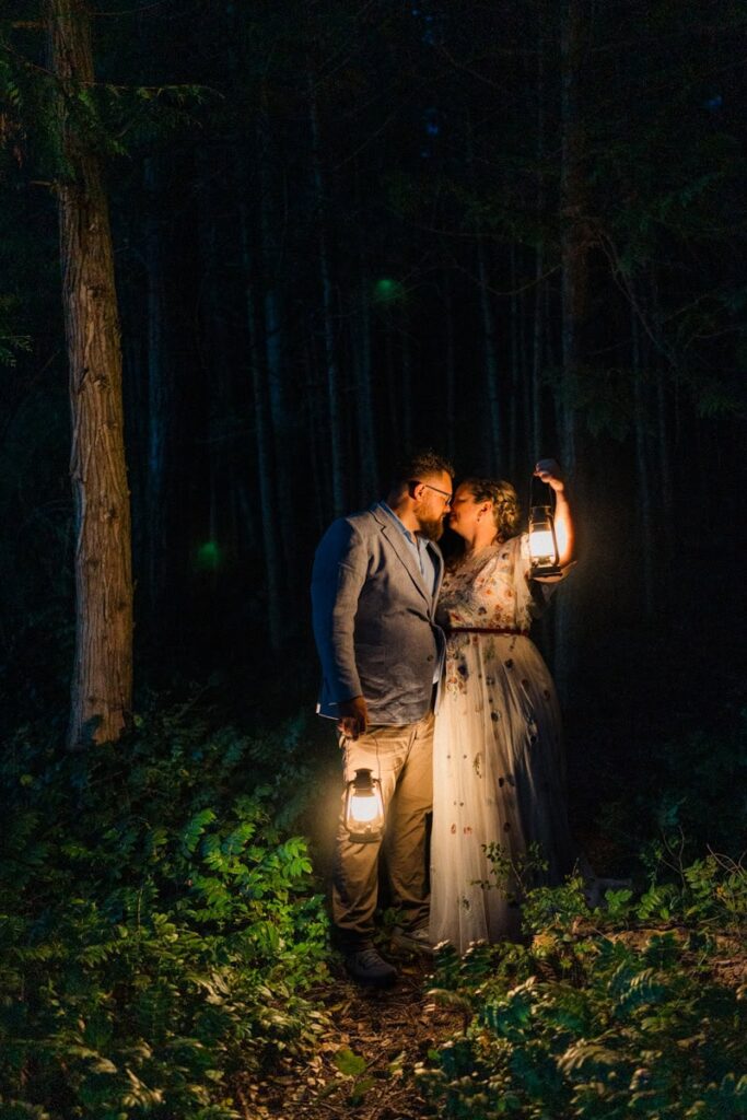a wedding couple holding lanterns in the trees at the end of their day during their Washington Elopement.