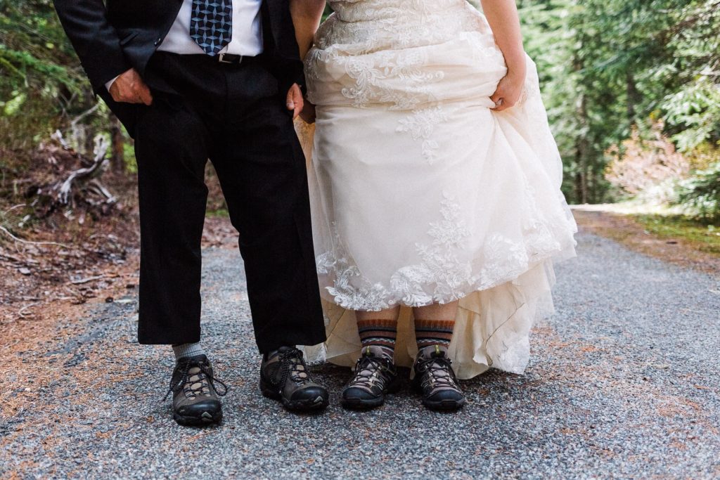 couple in wedding attire showing hiking boots on trail