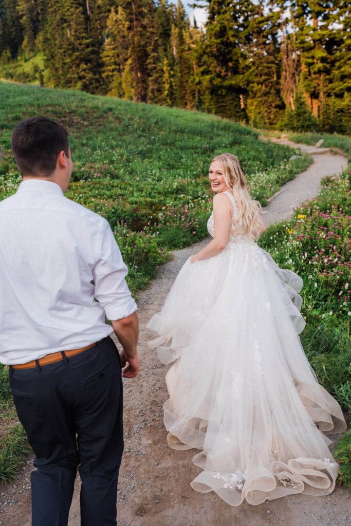 couple running on the trail through a wildflower meadow during their Mount Rainier National Park Elopement