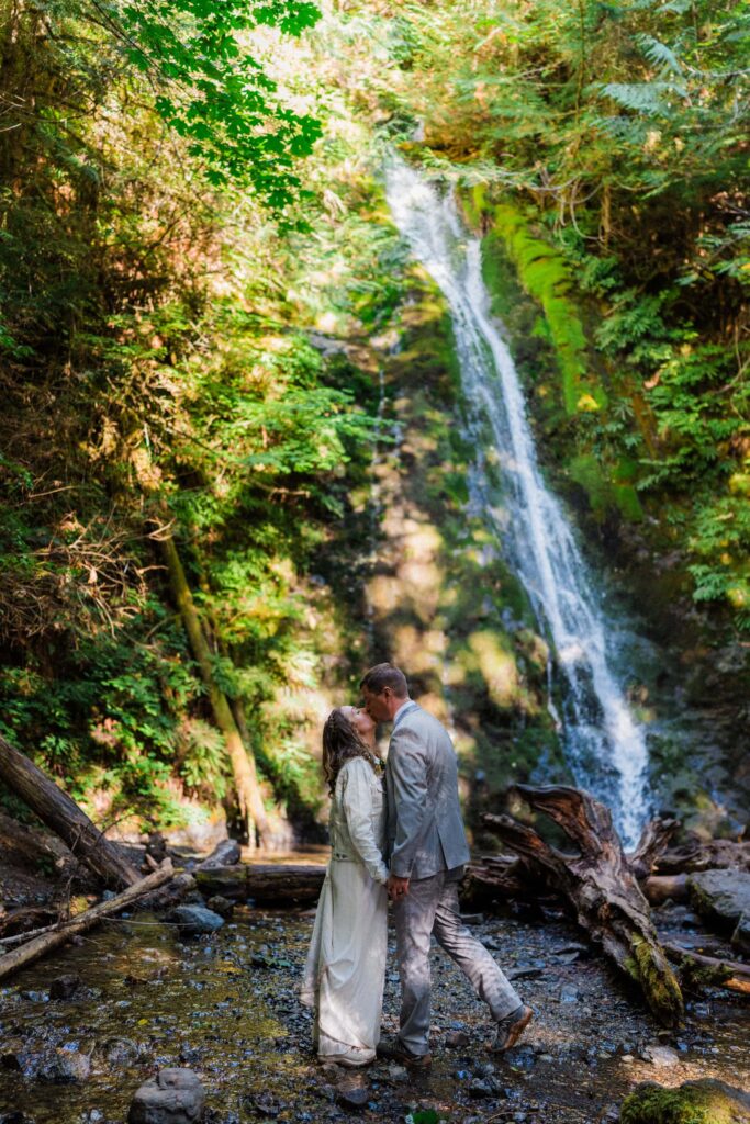 an eloping couple kissing under Madison Falls in Washington state.