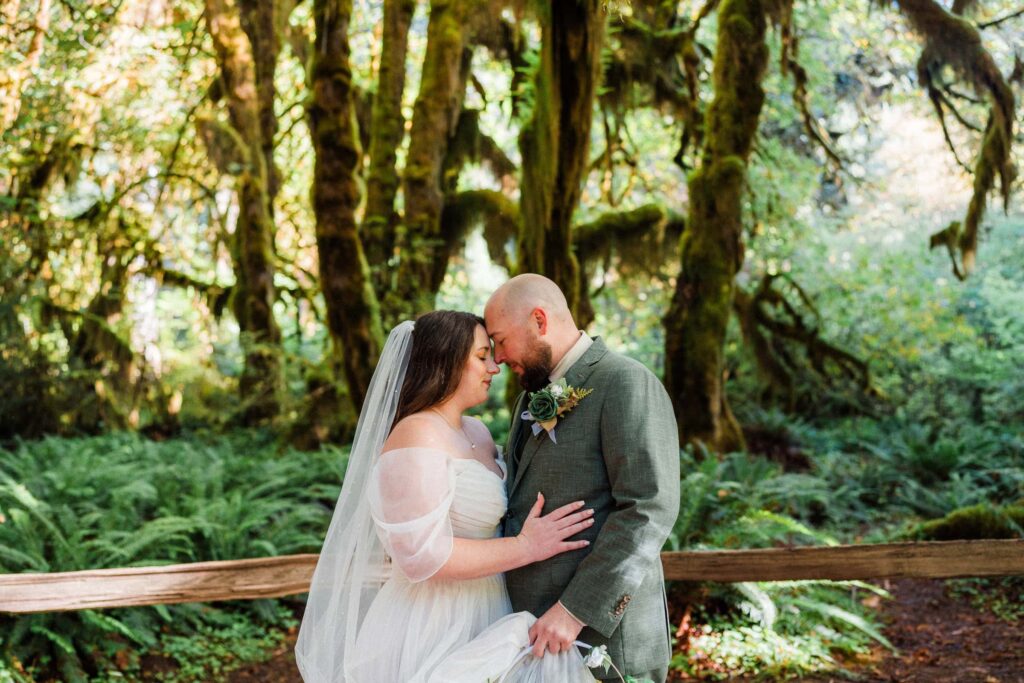 couple in wedding attire touching foreheads in the rainforest in Olympic National Park