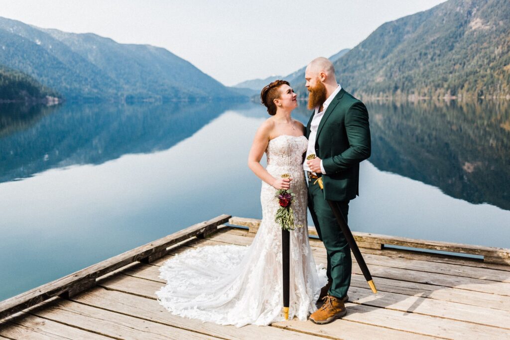married couple standing with swords on a doc at lake crescent in Olympic National Park