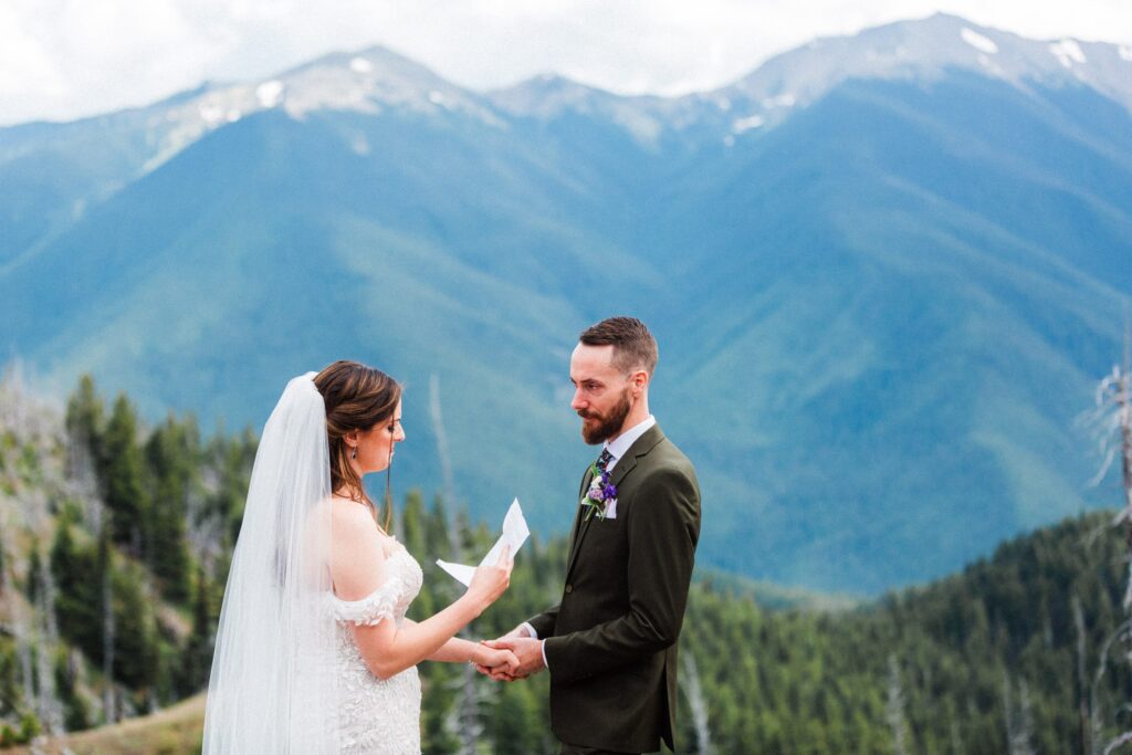 wedding couple reading vows to each other with mountain views in the background