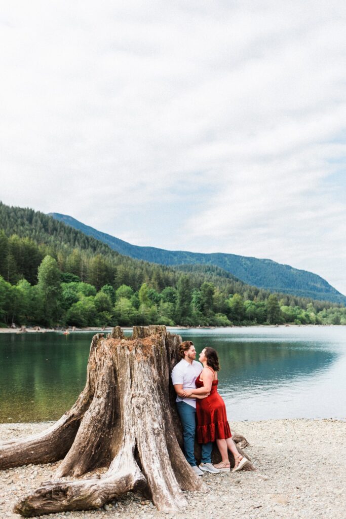 a couple cuddling against an exposed tree stump at Rattlesnake Lake